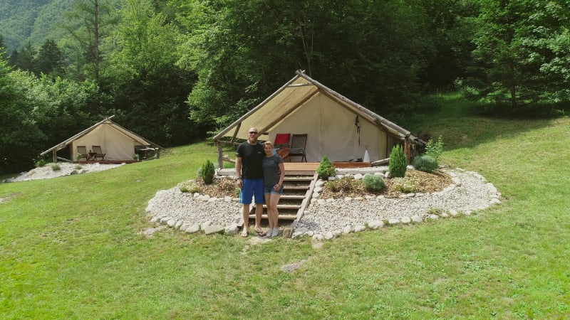 Aerial view of couple standing in front of sitting area at a camping site.