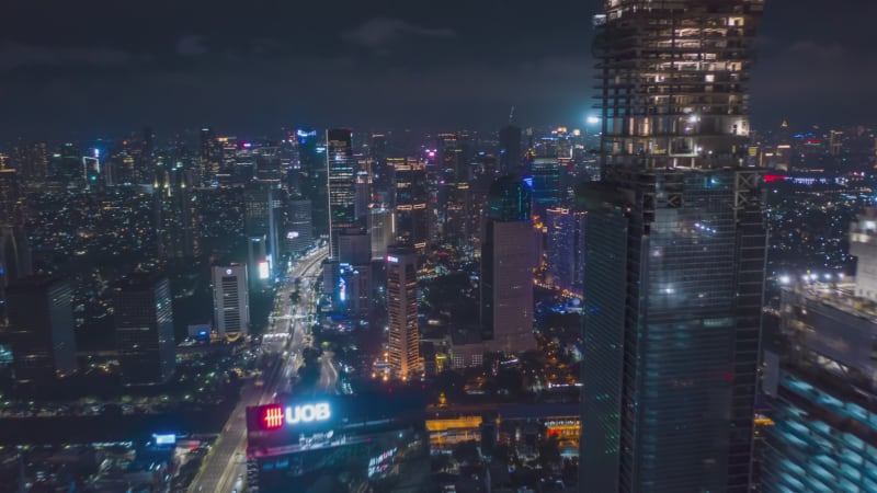 Hyper Lapse Motion Time Lapse at Night above of modern city center with skyscrapers and busy car traffic in futuristic modern Jakarta, Indonesia, Aerial Drone hyperlapse Establishing Shot