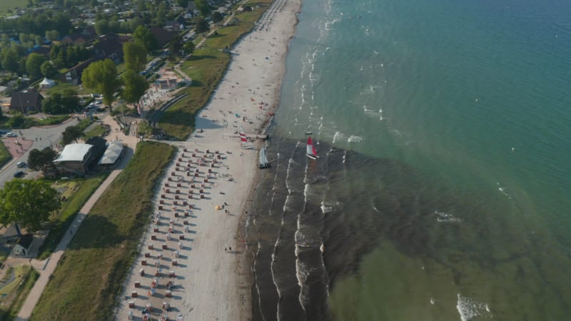 Aerial drone view of two sailboats in tourist beach at Baltic sea coastline, Scharbeutz, Germany, circle pan, day