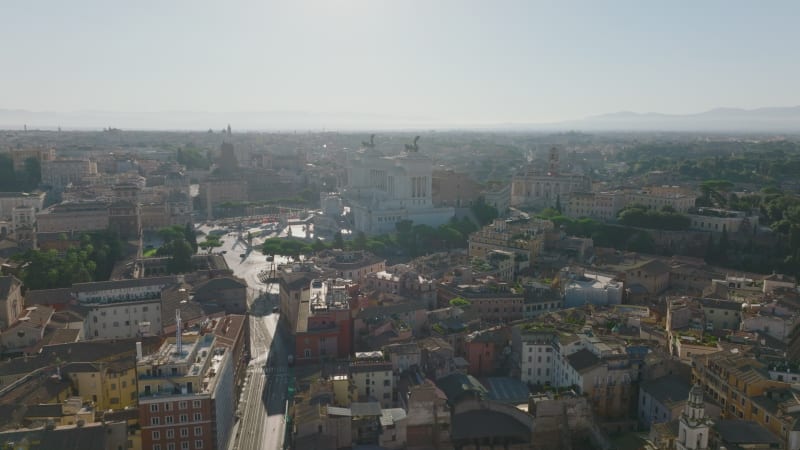 Aerial slide and pan footage of buildings in urban borough. Majestic Vittoriano monument with statues of goddess Victoria riding on quadrigas. Rome, Italy