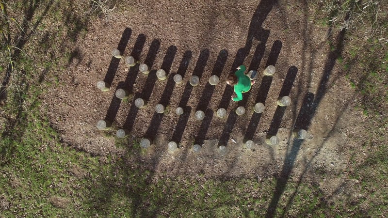 Aerial view of man jumping over wooden stumps.