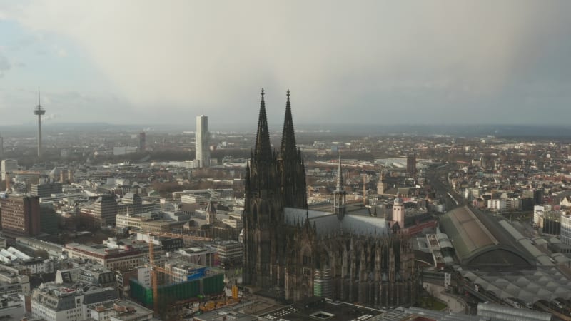 Slide and pan aerial footage of historic gothic cathedral with decorated tall towers. Panoramic view of town development. Cologne, Germany