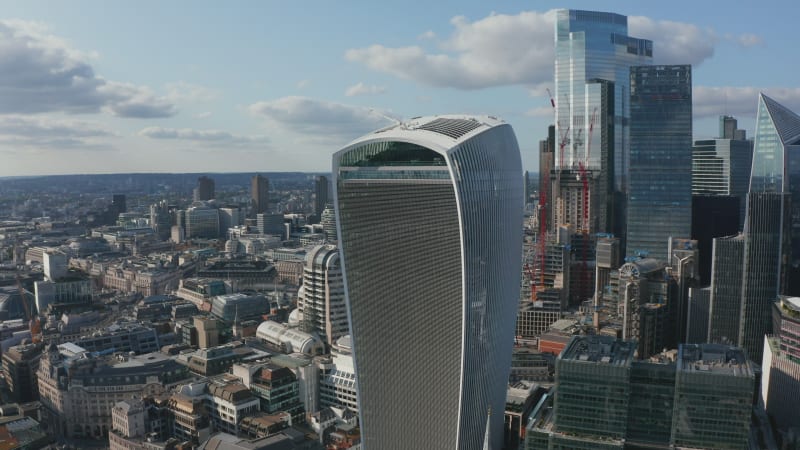 Fly around The Walkie Talkie skyscraper, tall modern futuristic iconic commercial building. Other skyscrapers in background. Revealing lower buildings in urban district. London, UK
