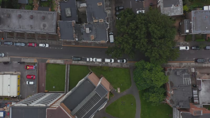 Aerial birds eye overhead top down tracking view of car giving way to oncoming traffic in narrow town street. London, UK