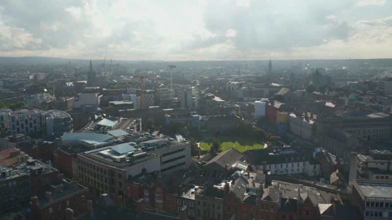 Slide and pan shot of town against sunshine. Aerial panoramic view of buildings in city centre. Dublin, Ireland