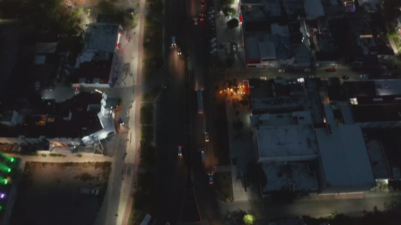 High angle view of road intersection. Tilt up reveal long straight busy street and panoramic view of city at night. Cancun, Mexico