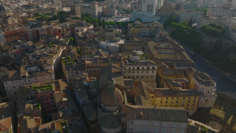 High angle view of old houses in urban borough. Tilt up reveal of Victor Emmanuel II Monument and Piazza Venezia square. Rome, Italy