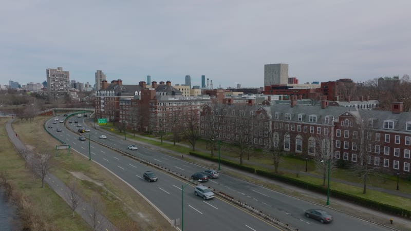 Busy multilane road leading on waterfront around Harvard university complex. Classical red brick buildings. Boston, USA