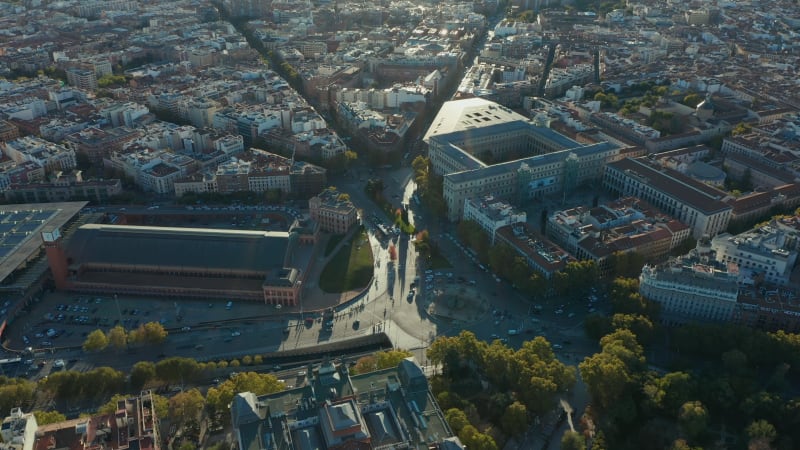 Amazing aerial view of heavy traffic on roads and various buildings around Atocha train station in late afternoon sunshine.