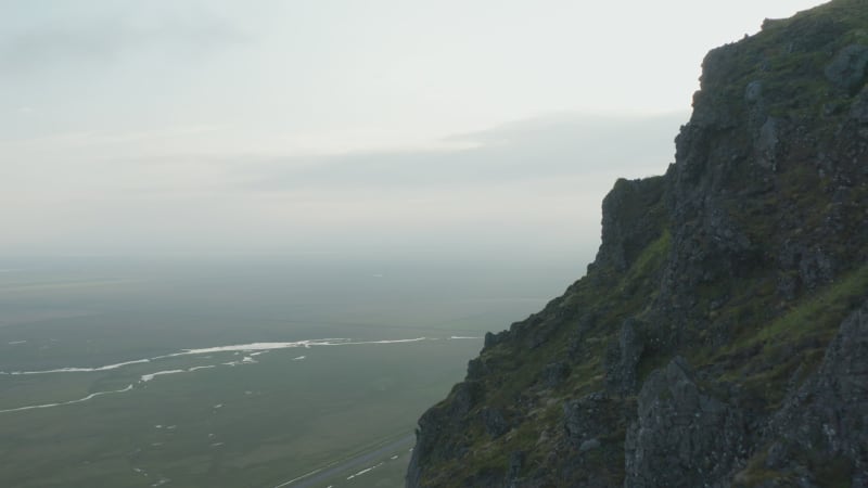 Birds eye drone view of rocky mossy cliffs in iceland countryside. Aerial view revealing southern icelandic moody highlands. Foggy landscape