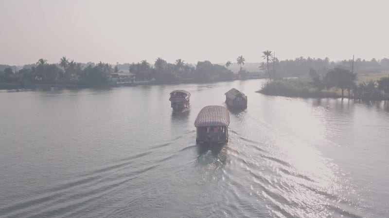 Indian wooden houseboats sailing on wide brown river