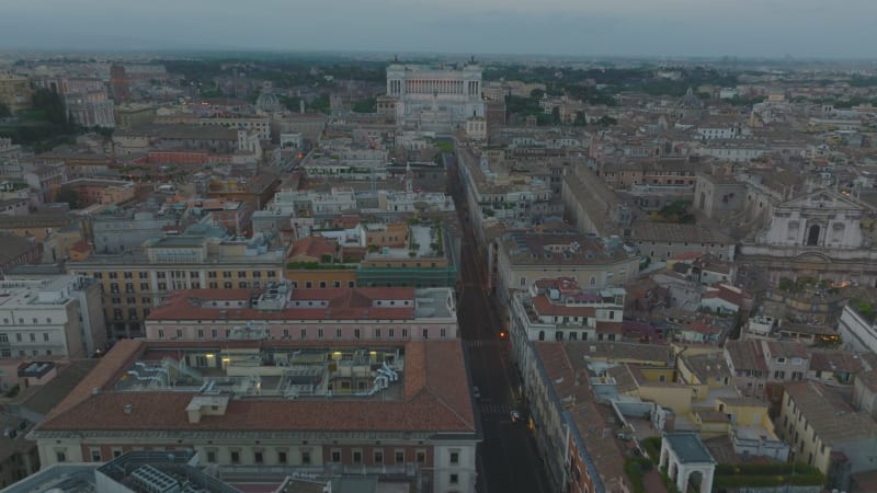 Forwards fly above historic buildings in city centre, landmarks and tourist sights. Heading towards Vittoriano monument at twilight. Rome, Italy