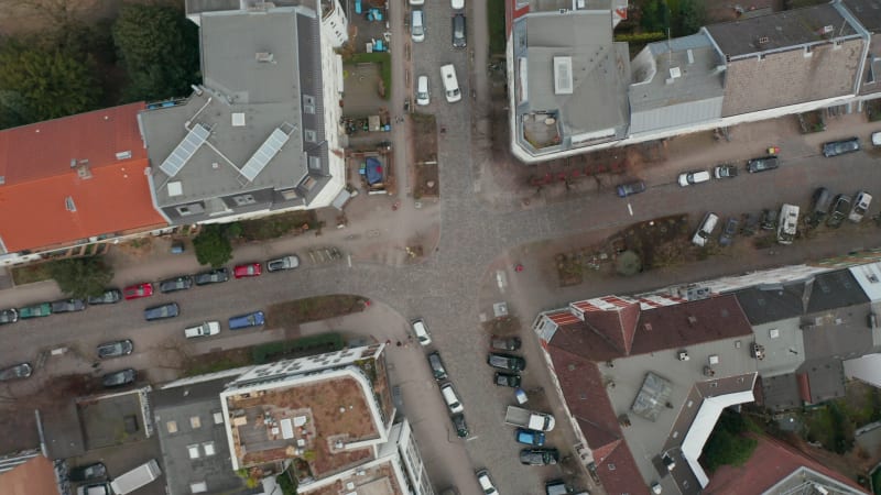 Descending aerial view of pedestrians and cars on street intersection in urban residential neighborhood in Hamburg