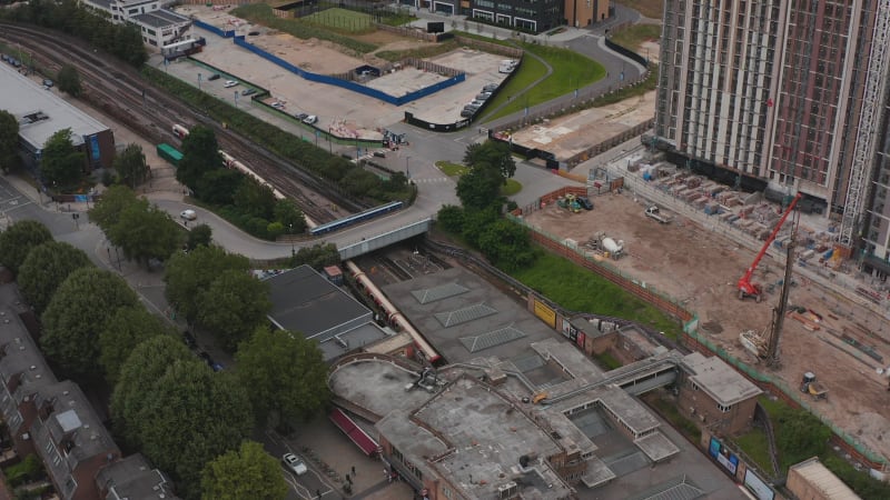 Landing footage of train arriving at White City train station. Construction site of new buildings in background. London, UK