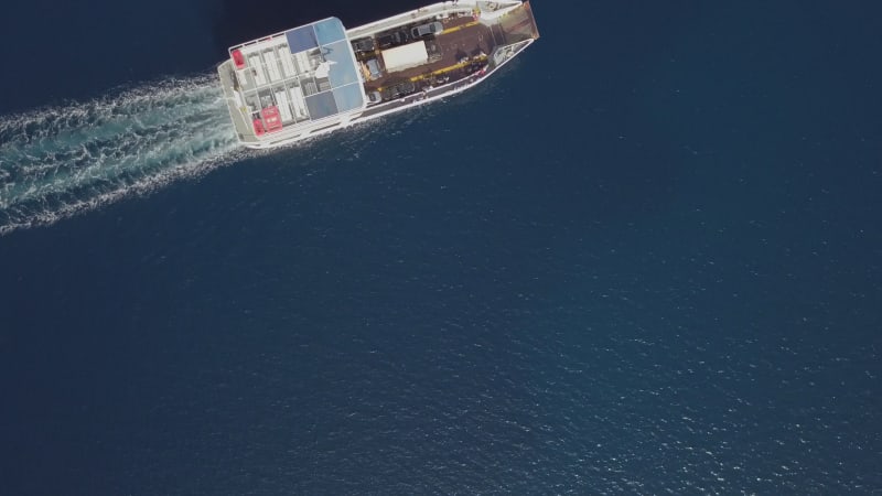 Aerial view above ferry boat with cars driving in the mediterranean sea.