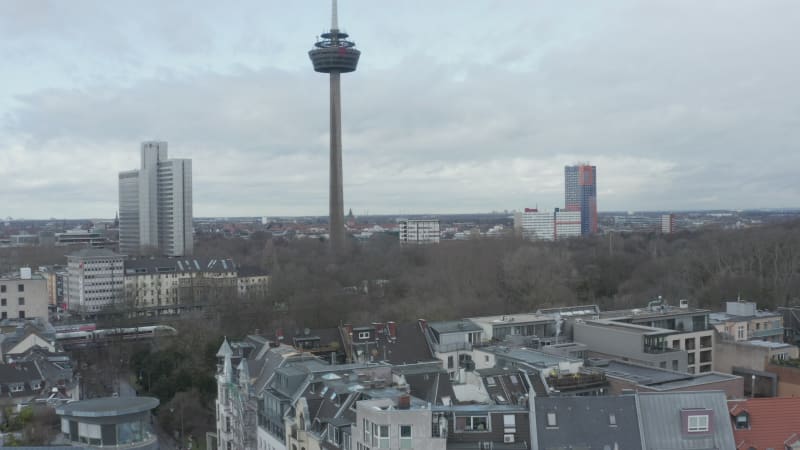 Residential neighbourhood and park with leafless trees. Cologne telecommunications tower exceeding surrounding development. Cologne, Germany