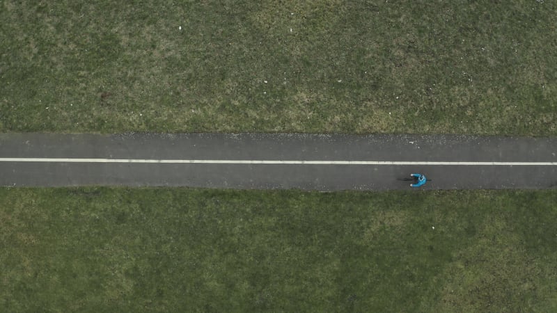 Top down view of a person in blue jacket cycling on the road