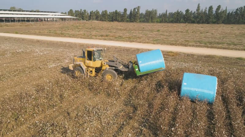 Aerial view of a tractor loading cotton bales on truck, Israel.