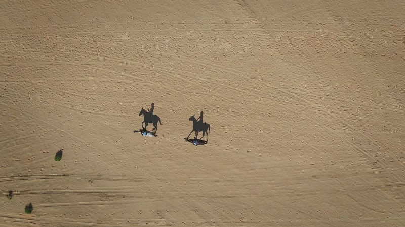 Aerial view of people riding horses in the desert of Al Khatim.