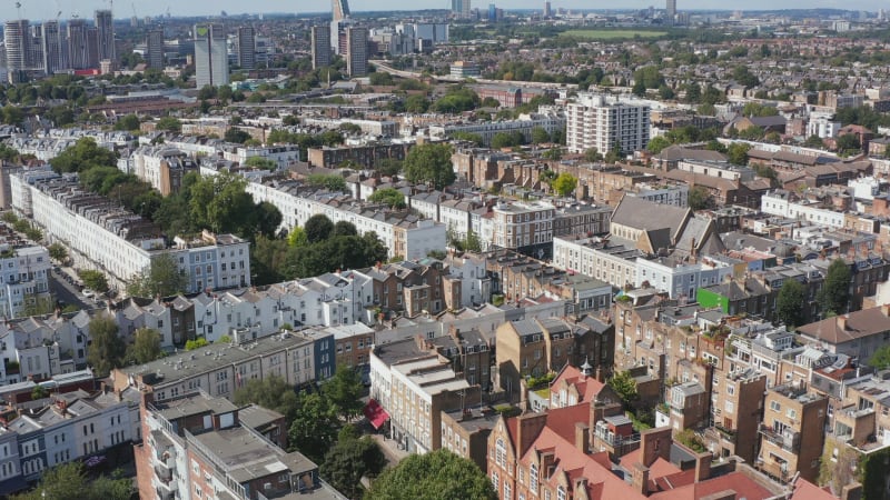 Forwards fly above rows of houses in urban neighbourhood. Aerial view of streets and homes. London, UK