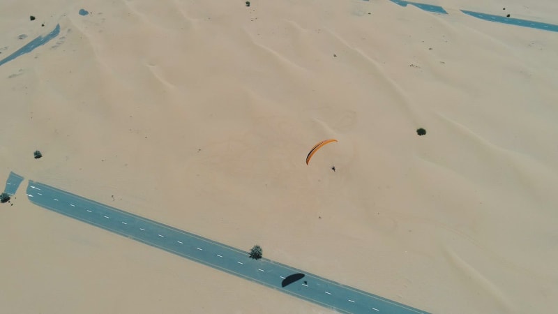 Aerial view of a man using powered parachute at desert landscape.