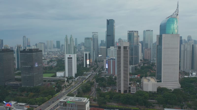 Aerial pedestal shot of busy city traffic driving in the modern city center with tall skyscrapers in Jakarta, Indonesia