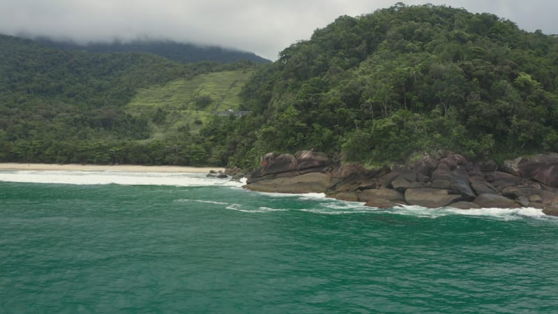 Rocky hills covered in lush vegetation rising above the tropical beach