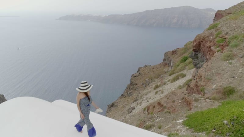 Aerial view woman walking on the roof on Santorini traditional house.