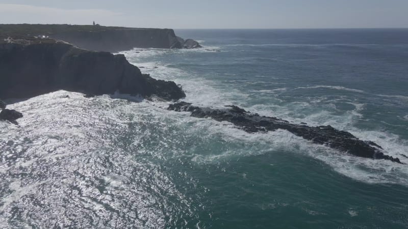 Aerial view of black cliffs in strong waves in