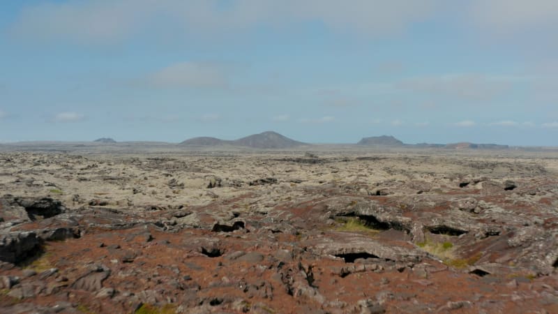 Aerial view over surreal and lunar landscape of Iceland. Drone view over rock desert with mountains in background