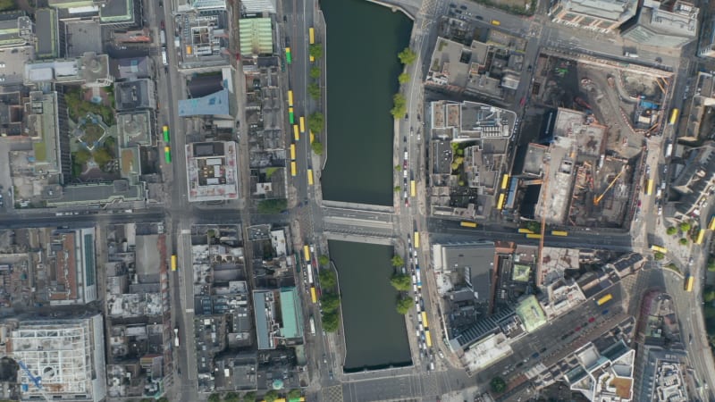 Aerial birds eye overhead top down view of water surface in town. Many yellow bus roofs in streets. Dublin, Ireland