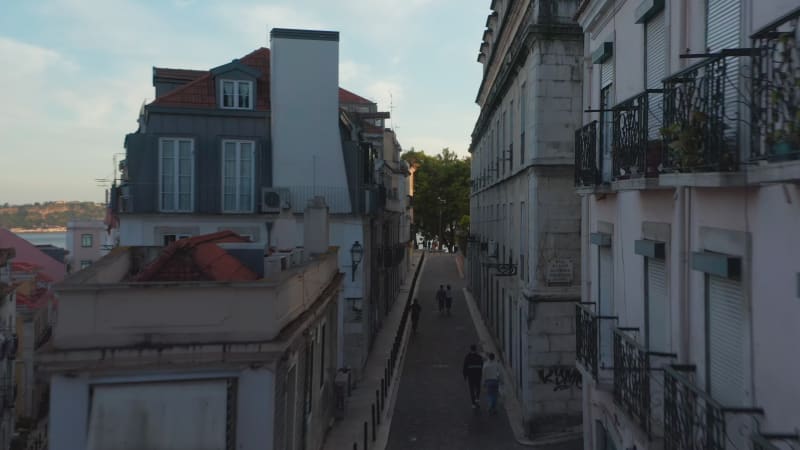 Drone camera flying through narrow street in town center. Evening elevated footage. Lisbon, capital of Portugal.