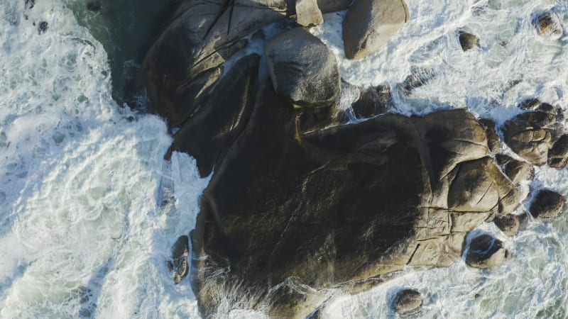 Top view powerful waves crashing against coastal rocks