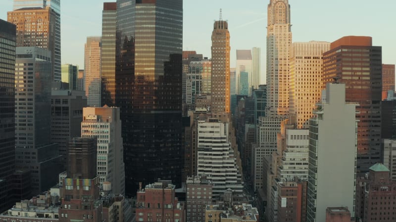 Modern high rise buildings with glossy glass facades reflecting colourful sunset sky. Manhattan, New York City, USA