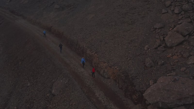 Aerial view four people backpacker hiking exploring isolated landscape in Iceland. Drone view friends tourist walking pathway in rocky icelandic desert