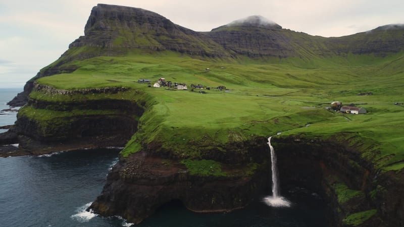 Aerial view of Múlafossur waterfall near a small village.