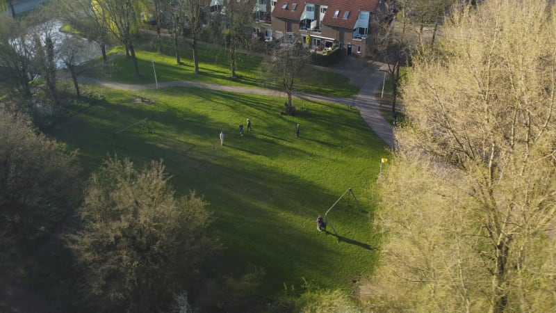 Aerial drone video of people playing football or soccer, on a sunny day, at a park in Houten, Netherlands.