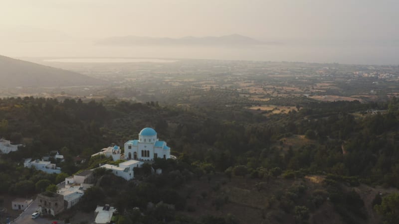 Greek cathedral with stunning blue roof in front of misty valley