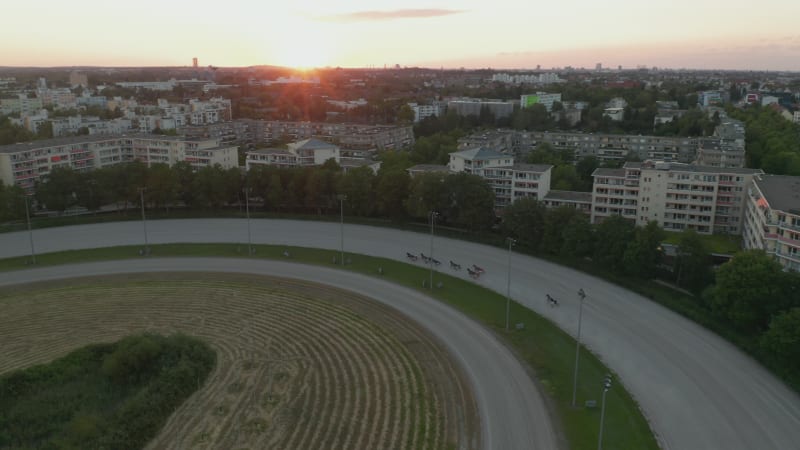 Harness Racers on Dirt Horse Race Track in Berlin, Germany at Sunset, Aerial follow tracking Shot from above