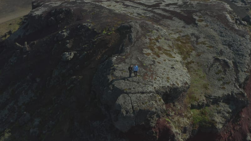 Drone view two people hikers enjoying panorama standing on hill in Iceland. Aerial view birds eye backpackers with drone recording and enjoying beauty in nature