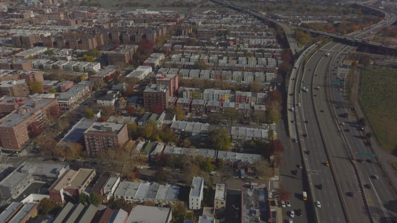 Rows of residential buildings in urban neighbourhood near multilane highway interchange. Aerial panoramic shot. Queens, New York City, USA