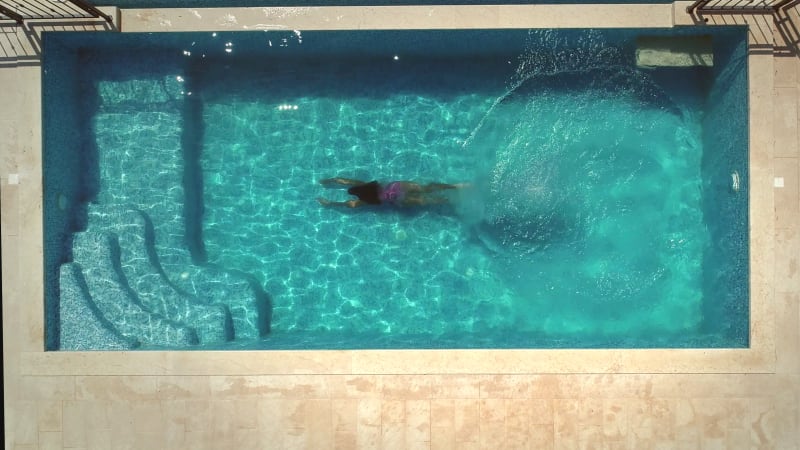 Aerial view of young woman diving into swimming pool.