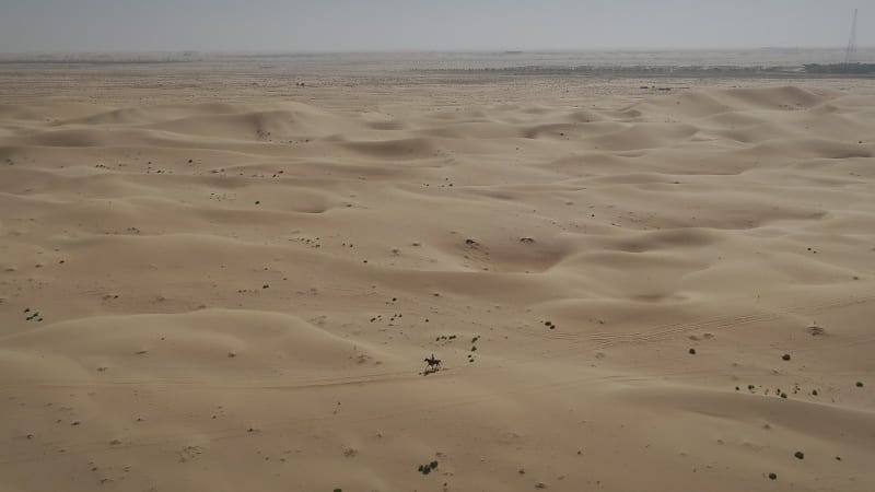 Aerial view of one person riding horse in the desert of Al Khatim.