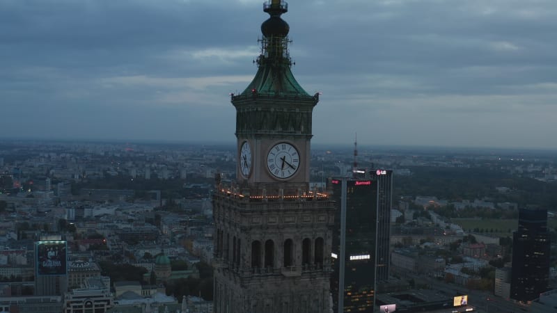 Orbit shot around tower with large tower clock. Top of PKIN historic high rise building at dusk. Warsaw, Poland