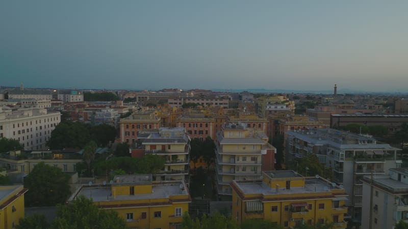 Forwards fly above buildings in urban borough. Apartment buildings in housing estate in large city at twilight. Rome, Italy