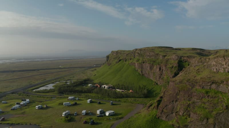 Drone view of amazing green countryside in Iceland. Aerial view drone flying over stunning icelandic landscape with caravan and touristic camper traveller. Amazing in nature travel destination