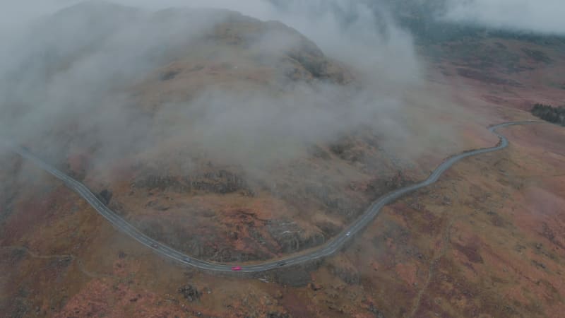 Cars driving up the mountain road into the fog