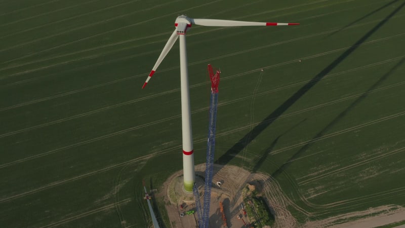 Close overhead drone view flight over Wind Turbine under construction being built on rich green agriculture field