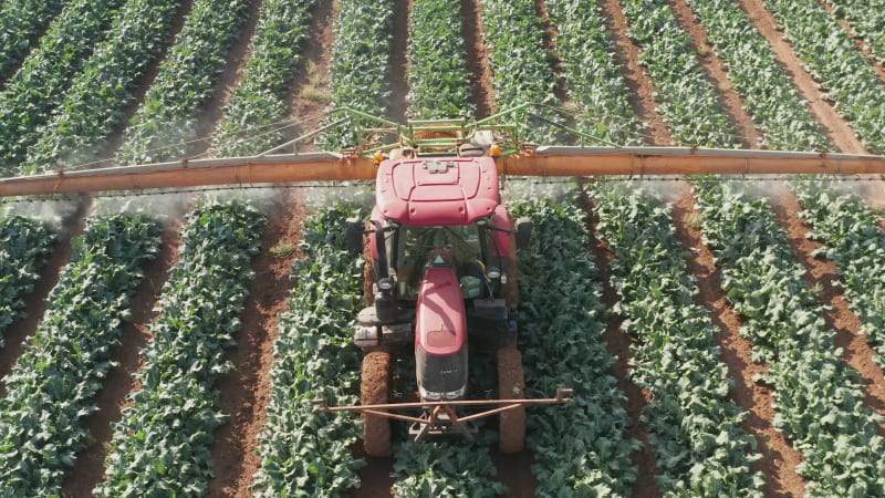 Pesticide Sprayer Tractor working on a large field, Aerial follow footage.