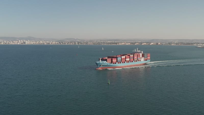 Large loaded Container Ship roaring across the open sea, Aerial view.